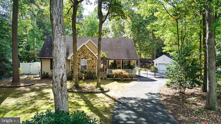 view of front facade featuring a garage, a porch, a front yard, and an outbuilding