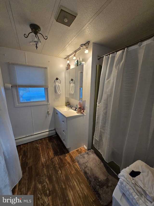 bathroom with hardwood / wood-style floors, vanity, a baseboard heating unit, a shower with shower curtain, and a textured ceiling