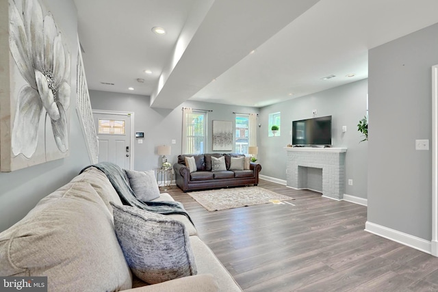 living room with wood-type flooring and a brick fireplace