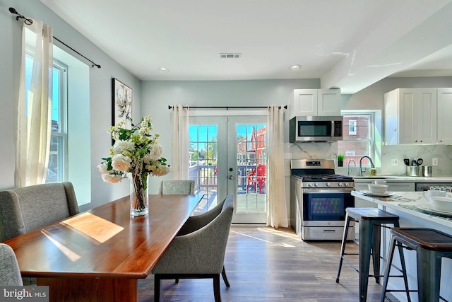 dining space with sink, french doors, and light hardwood / wood-style flooring