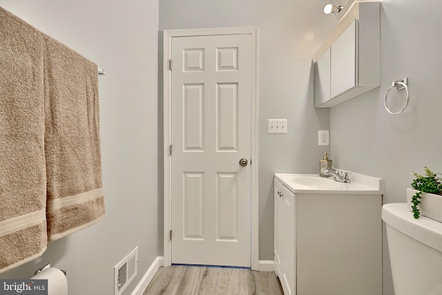 bathroom with toilet, vanity, and hardwood / wood-style flooring