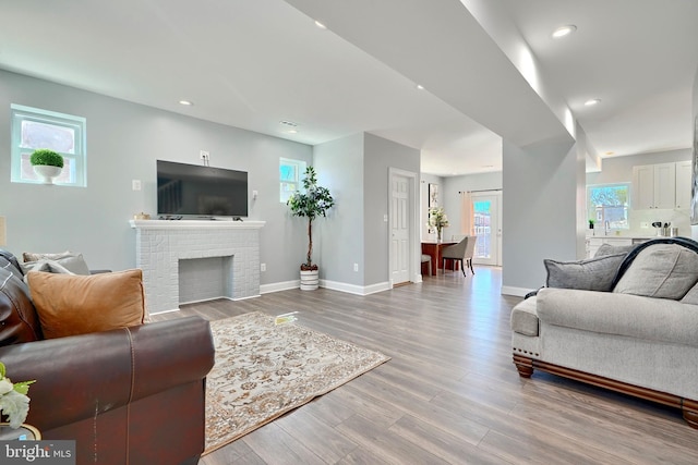 living room featuring plenty of natural light, light hardwood / wood-style floors, and a brick fireplace