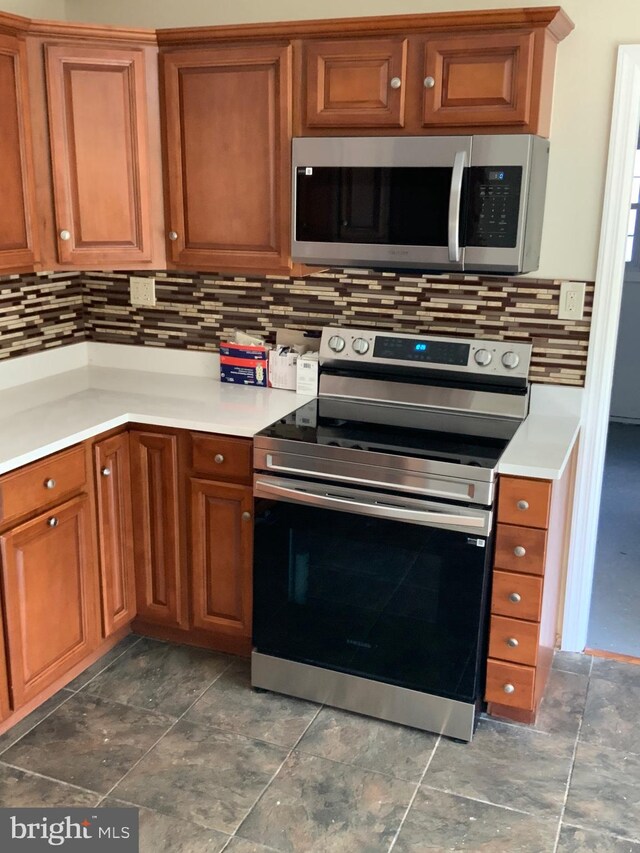 kitchen featuring backsplash, brown cabinets, light countertops, and appliances with stainless steel finishes