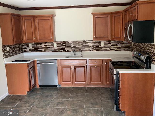 kitchen with a sink, brown cabinetry, stainless steel appliances, and backsplash