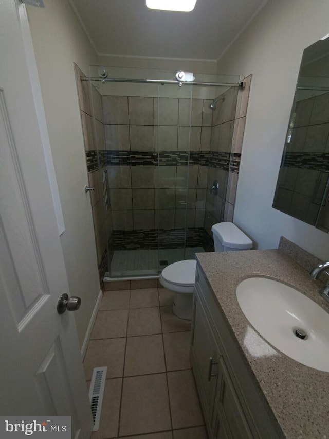 bathroom with toilet, vanity, tile patterned flooring, and a shower with shower door