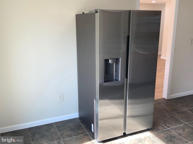 kitchen with baseboards, stainless steel fridge with ice dispenser, and dark tile patterned flooring