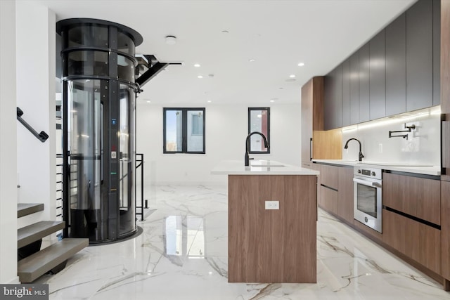 kitchen featuring sink, oven, and an island with sink