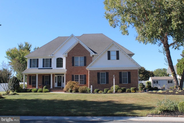 view of front of home featuring brick siding, fence, and a front lawn