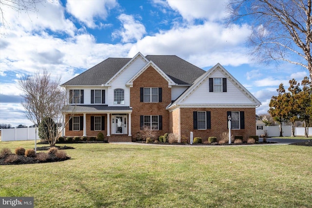 view of front of property featuring a front yard, brick siding, and fence