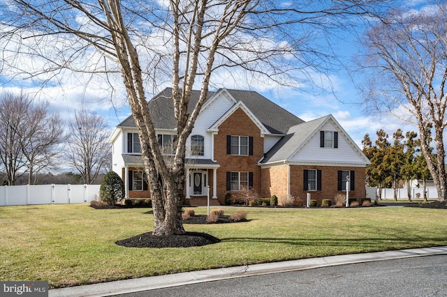 view of front of house with a front yard, fence, and brick siding