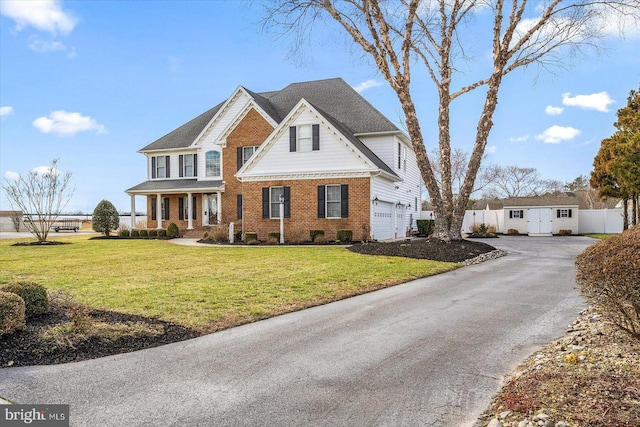 view of front of house with driveway, fence, a front lawn, and brick siding