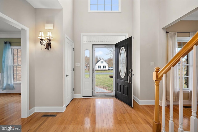 foyer entrance featuring a wealth of natural light, light wood-type flooring, visible vents, and baseboards