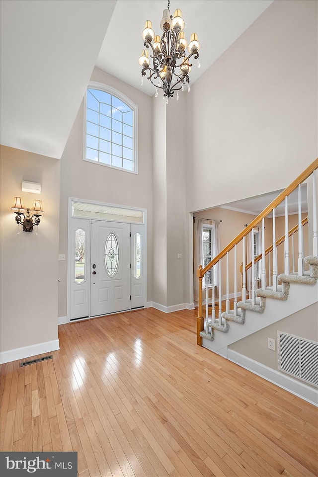 foyer entrance with stairway, visible vents, a wealth of natural light, and hardwood / wood-style floors