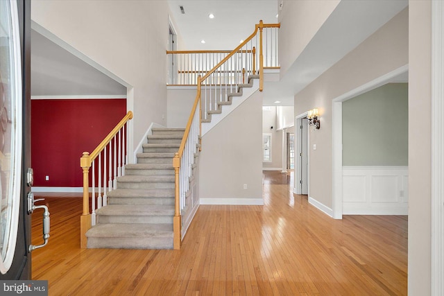 entrance foyer featuring recessed lighting, a towering ceiling, baseboards, stairs, and wood-type flooring