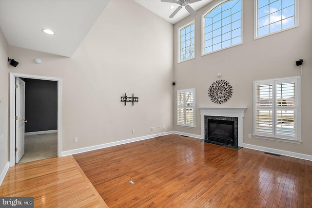 unfurnished living room with visible vents, a fireplace, hardwood / wood-style flooring, and baseboards