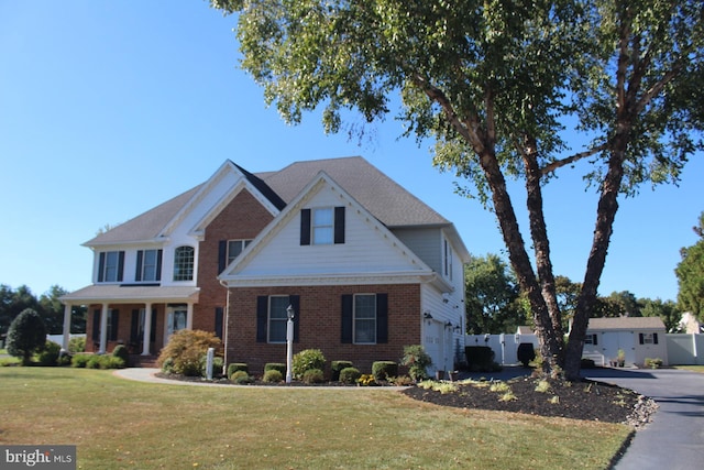 view of front facade with aphalt driveway, a front yard, brick siding, and fence