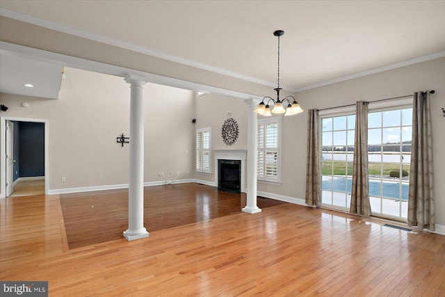 unfurnished living room featuring ornamental molding, a premium fireplace, decorative columns, and light wood-style floors