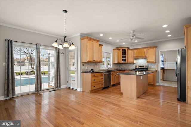 kitchen featuring appliances with stainless steel finishes, a kitchen island, backsplash, and light wood finished floors