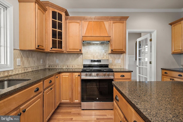 kitchen with crown molding, light wood-style flooring, wall chimney exhaust hood, and gas range