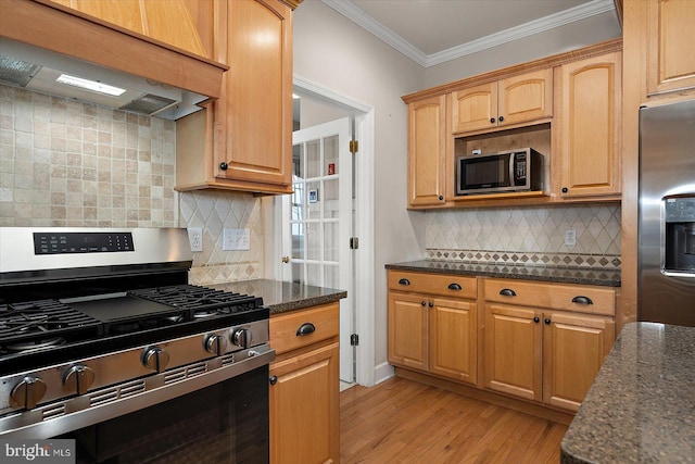 kitchen with dark stone counters, custom range hood, appliances with stainless steel finishes, ornamental molding, and light wood-style floors