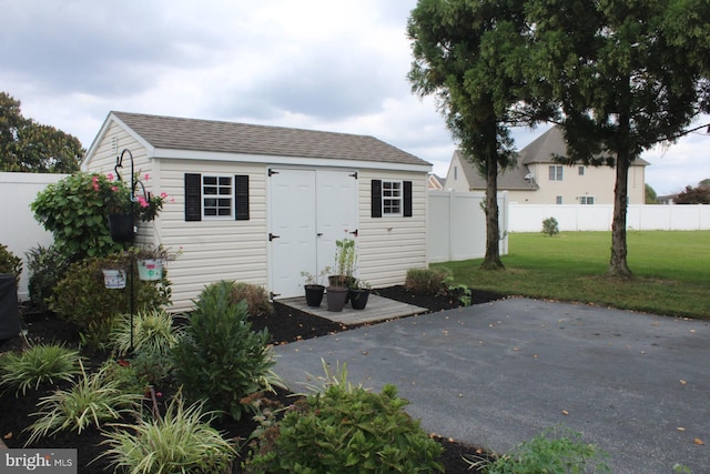 exterior space featuring a patio, a fenced backyard, an outbuilding, a storage unit, and a front lawn