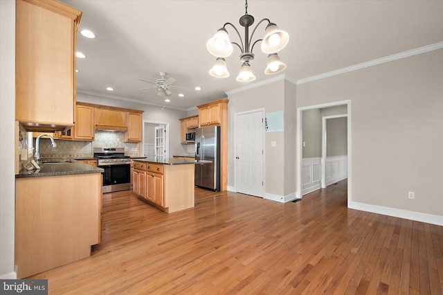 kitchen with stainless steel appliances, a kitchen island, a sink, light wood-style floors, and tasteful backsplash