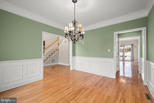 unfurnished dining area featuring stairway, light wood-style flooring, visible vents, and a chandelier