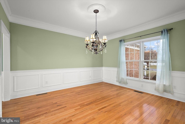 unfurnished dining area featuring light wood finished floors, visible vents, and ornamental molding