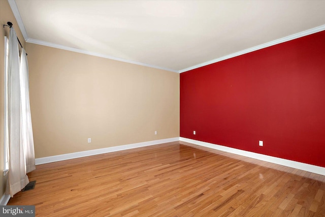 unfurnished room featuring ornamental molding, light wood-type flooring, visible vents, and baseboards