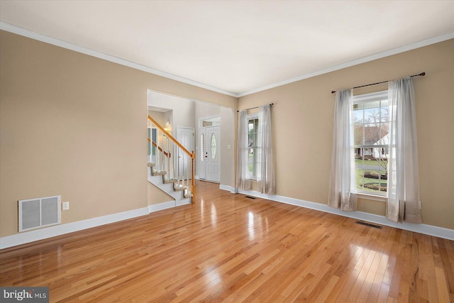 spare room with stairs, light wood-style flooring, visible vents, and baseboards