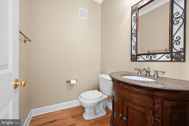 bathroom featuring toilet, wood finished floors, vanity, visible vents, and baseboards