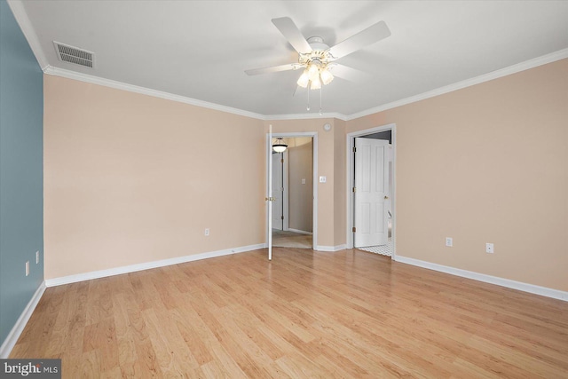 spare room featuring crown molding, light wood finished floors, visible vents, and baseboards