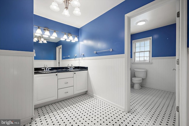 bathroom featuring a wainscoted wall, a sink, and an inviting chandelier