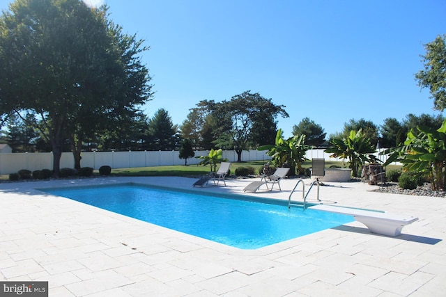 view of pool featuring a fenced in pool, a patio area, a fenced backyard, and a diving board