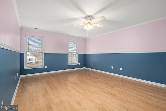 empty room featuring wood finished floors, visible vents, baseboards, a ceiling fan, and ornamental molding