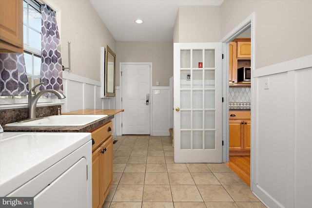 kitchen with light tile patterned floors, tasteful backsplash, washer / clothes dryer, stainless steel microwave, and a sink