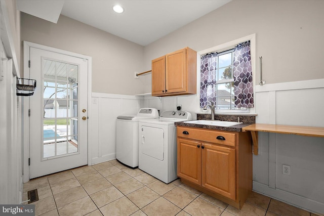 washroom featuring a wainscoted wall, washing machine and dryer, plenty of natural light, and a sink