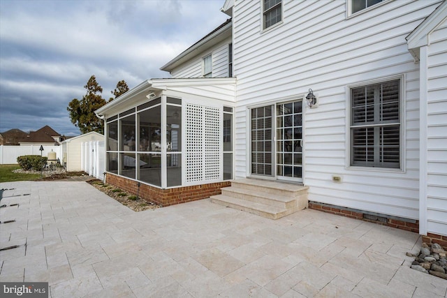 view of patio with entry steps, a sunroom, an outdoor structure, and a storage unit