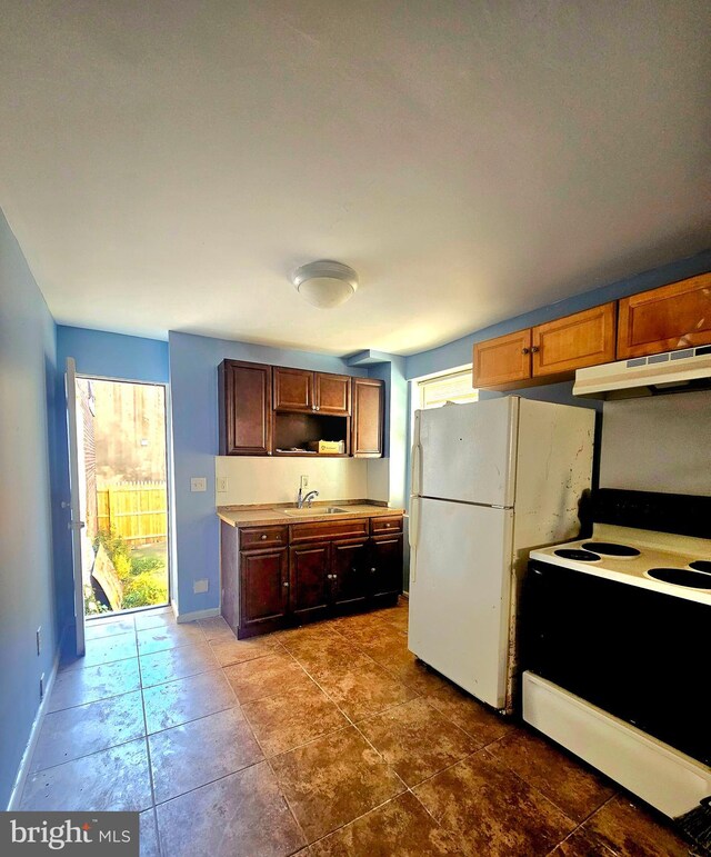 kitchen featuring dark tile patterned floors, sink, range hood, and white appliances