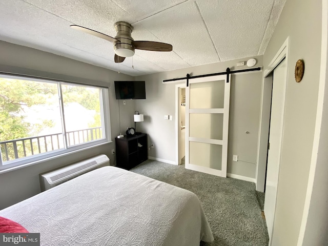 carpeted bedroom featuring a closet, baseboards, multiple windows, and a barn door