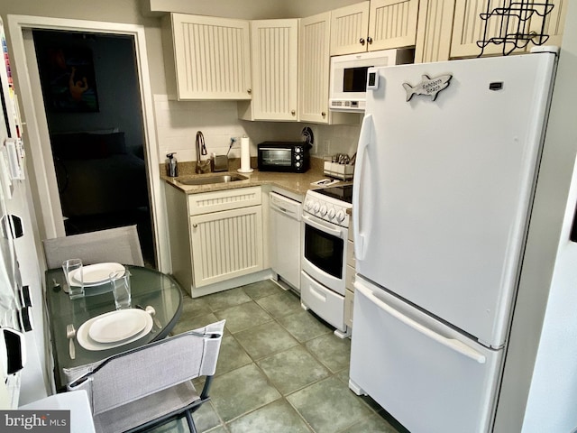 kitchen featuring white appliances, light tile patterned floors, light countertops, cream cabinets, and a sink
