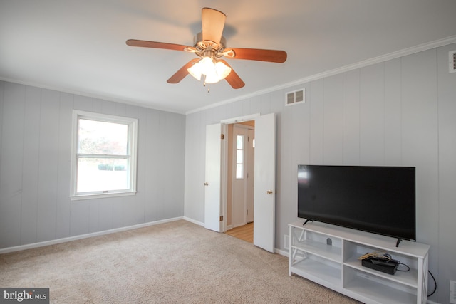 carpeted living room with ceiling fan and ornamental molding