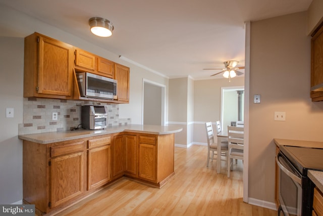 kitchen with light wood-type flooring, ceiling fan, decorative backsplash, kitchen peninsula, and appliances with stainless steel finishes