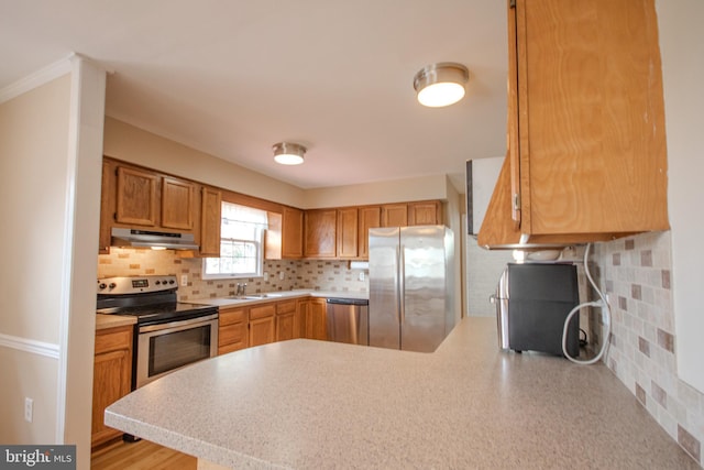 kitchen with appliances with stainless steel finishes, kitchen peninsula, decorative backsplash, and sink