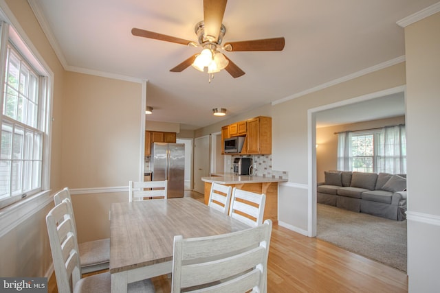 dining space with ornamental molding, a healthy amount of sunlight, ceiling fan, and light hardwood / wood-style flooring