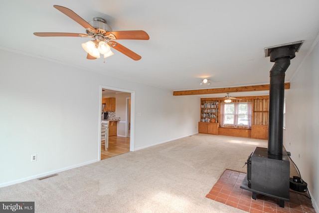 unfurnished living room with a wood stove, ceiling fan, and carpet floors