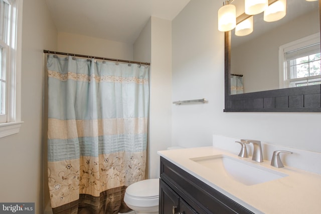 bathroom with walk in shower, vanity, and toilet