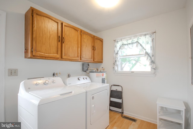 laundry room with washing machine and clothes dryer, cabinets, light hardwood / wood-style floors, and electric water heater