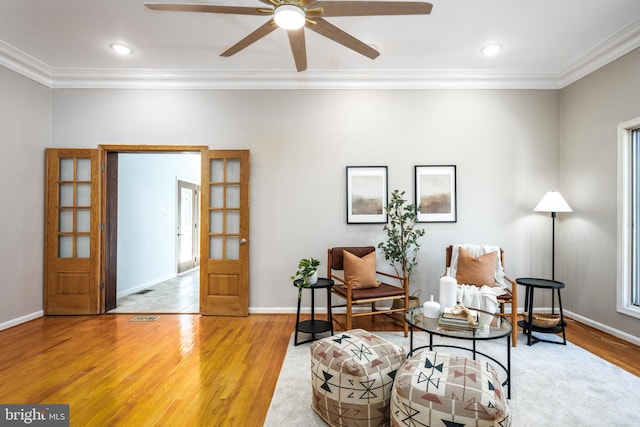 living area with crown molding, light hardwood / wood-style floors, and ceiling fan