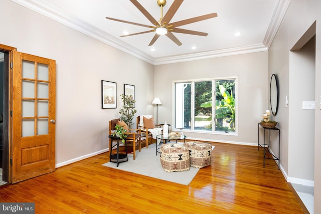 living area with ceiling fan, wood-type flooring, and ornamental molding